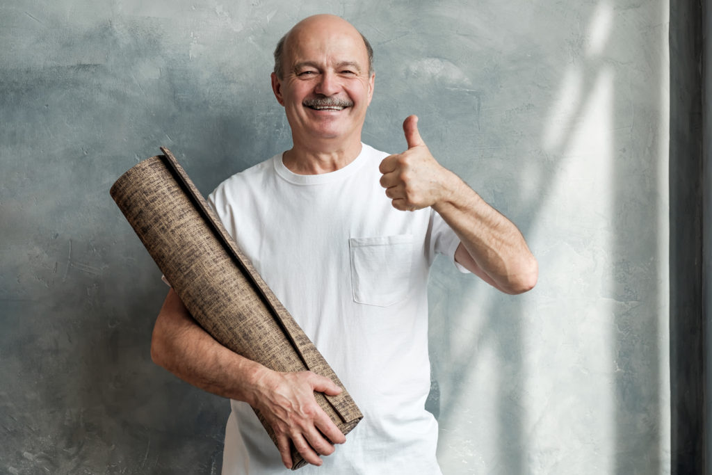 Mature man with yoga mat ready to train